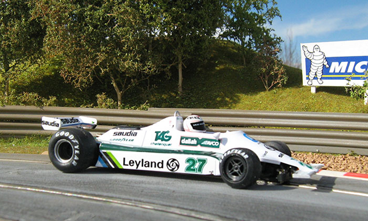Click To Enlarge. A close-up of an FW07 Formula One car taking a bend on a race track.
